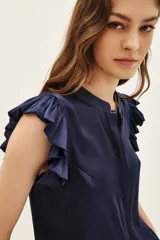 Camisa negra de poliéster con corte recto, cuello mao y volados en las mangas.