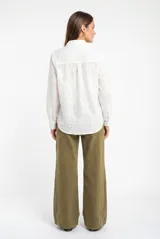 Camisa de corte oversize confeccionada en algodón con diseño de broderie. Presenta cuello clásico, cierre frontal con botones y mangas largas con puños rectos.