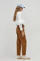 Camisa blanca de popelina de algodón con cuello clásico y botones de nácar. Presenta volados dobles decorativos que recorren el frente y la espalda desde el hombro hasta la cintura, además de volados en las mangas a la altura del codo.