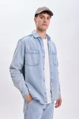 Sobrecamisa de jean celeste con cuello clásico, cierre frontal con botones metálicos, dos bolsillos de parche en el pecho y mangas largas con puños abotonados.