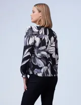 Blusa de gasa estampada con flores en tonos negro, gris y blanco, marca Zac & Rachel. Cuello a la base y abertura central con botones. Delantera con detalle fruncido.