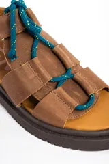 Sandalias de cuero color marrón, con suela track marrón oscura y cordones estilo marinero en color verde azulado que cruzan la capellada.
