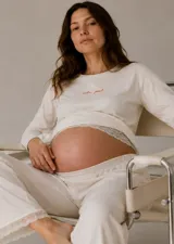 Conjunto de pijama compuesto por una remera de manga larga con detalle de bordado en el pecho y un pantalón de corte holgado. Ambas prendas presentan terminaciones con encaje en los bordes.