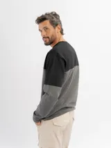 Buzo de felpa de diseño colorblock con cuello redondo, mangas largas y puños de rib, combinando negro en la parte superior y azul en la inferior y mangas.