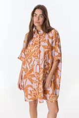 Camisa de lino y algodón, color rosado con estampado floral en tonos naranjas. Presenta cuello mao, manga corta con puño, botones de metal a la vista y ruedo camisero con tajos laterales.