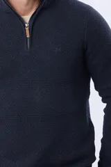 Buzo tejido texturado color beige, con cuello alto y cierre frontal parcial con detalle de cuero.