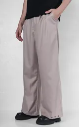 Pantalón sastrero de corte oversize en color beige, con pinzas frontales profundas que aportan volumen y movimiento. Presenta cintura ancha, bolsillos laterales y bolsillos tipo ojal en la parte trasera, con detalle de botones en el ruedo.
