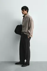 Camisa de corte regular confeccionada en lino, con cuello solapa y cierre frontal de botonadura oculta. Presenta mangas largas con puños abotonados.