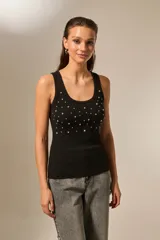 Musculosa negra de bretel fino, con cuello redondo profundo y diseño ajustado al cuerpo. Presenta detalles de studs y strass en la parte frontal.