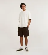 Bermuda masculina color marrón oscuro, confeccionada en tela French Terry, con cintura elástica y cordón de ajuste. Presenta bolsillos cargo funcionales a los lados.