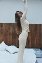 Pantalón negro de tejido de punto, tiro alto, con cintura elástica y detalle de tres botones frontales. Corte de pierna recta y ancho.