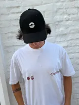 Gorro tipo jockey negro con visera curva y logo frontal bordado en blanco, que representa un semicírculo dividido horizontalmente.