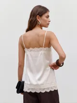 Top negro de satén, de corte recto, con escote cuadrado, breteles finos y detalles de encaje floral transparente en el escote y en el borde inferior.