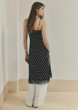Top largo de tejido satinado color negro con estampado de lunares blancos, diseño recto, tirantes finos y ribetes de encaje negro en el escote y el ruedo.