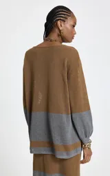 Sweater de punto calado con diseño de bloques de color en tonos marrón y gris. Presenta escote barco, mangas largas con puños ajustados en color gris y corte recto.