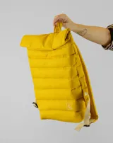 Mochila acolchada color amarillo, con diseño de cierre enrollable en la parte superior y correas ajustables en color beige. Presenta un pequeño logo bordado en la parte inferior frontal.
