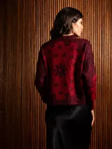 Buzo de punto de manga larga con cuello redondo, confeccionado en un tejido suave de textura peluda. Presenta un diseño estampado con motivos florales y ornamentales en color negro sobre una base de color rojo intenso.