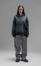 Hoodie oversize de corte crop en color gris oscuro con efecto desgastado. Presenta costuras expuestas, detalles de roturas en el ruedo y en la capucha, y bolsillos frontales con bordes reforzados.