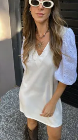 Vestido corto color crudo, con escote en V y mangas 3/4 abullonadas con detalles de calado.