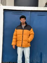 Campera puffer color mostaza con cuello alto y cierre frontal con cremallera.