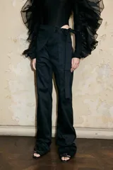 Pantalón negro de sarga de cintura alta con centro redondeado y cinturón desmontable con forma de silla de montar.