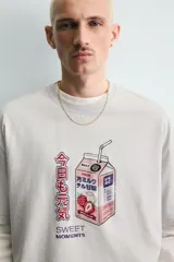 Camiseta relaxed fit color beige con cuello redondo y manga corta. Presenta un estampado frontal de un cartón de leche de fresa con una pajita, texto en japonés y la frase "SWEET MOMENTS".