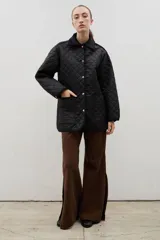 Campera acolchada de corte holgado, color blanco con diseño capitoneado en forma de rombos. Presenta cuello camisero y bordes internos con estampado floral en tonos azul y rojo, cierre frontal con botones a presión y bolsillos laterales.