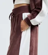 Pantalón wide leg de textura aterciopelada color bordó, con cintura elástica ajustable mediante lazo y franjas laterales en contraste.