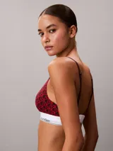 Bralette Calvin Klein de corte triangular, confeccionado en mezcla de algodón elástico y modal, con estampado gráfico en tonos rojos y banda elástica inferior en color blanco con el nombre de la marca en contraste.