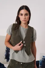 Chaleco de gabardina color blanco, con escote en V, cierre frontal con botones y bolsillos delanteros simulados.