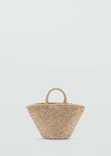 Bolso tipo canasta de tamaño pequeño, confeccionado en fibra natural trenzada con un diseño de red superpuesto en color blanco. Cuenta con dos asas cortas de mano y una estructura abierta sin cierre.