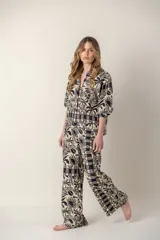 Pantalón de dama con estampado de hojas, flores y soles en tonos beige y negro.