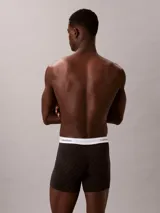 Pack de tres bóxers Calvin Klein tipo boxer brief de algodón elástico. Incluye un modelo negro con monograma estampado, uno azul oscuro liso y uno gris claro liso. Todos cuentan con cintura elástica blanca con el logo de la marca.