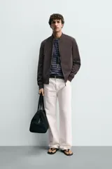 Cazadora bomber ligera de tejido técnico color verde oliva, con cuello, puños y bajo en rib elástico. Presenta cierre frontal de cremallera y bolsillos de vivo en la cadera.