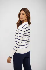 Buzo de tejido de punto color blanco con rayas horizontales azul marino. Presenta cuello redondo y mangas largas con puños y ruedo en azul marino.