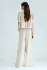 Pantalón de corte holgado en sarga suave color beige. Modelo con cintura elástica estándar, bolsillos en las costuras laterales y piernas rectas.