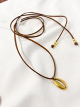 Gargantilla con cordón marrón de gamuza sintética y dije dorado en forma de concha.