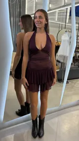 Vestido corto bordó con escote halter, diseño ajustado en el torso de tela translúcida y falda corta con doble volante fruncido.