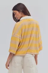 Remera tipo polo de algodón, de calce oversize, con diseño a rayas en tonos azul y celeste, cuello clásico blanco, botonadura corta, hombros caídos y mangas cortas.