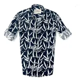 Camisa de manga larga negra con estampado de hojas blancas, cuello clásico y cierre con botones.