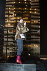 Abrigo corto de piel sintética color marrón, con cuello alto y bolsillos colgantes sujetos con cadenas.