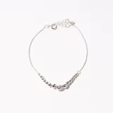 Pulsera plateada de cadena fina con cierre de mosquetón y cadena de alargue. Presenta una hilera de bolitas plateadas, con una bolita facetada en el centro.