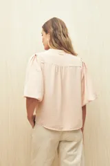 Blusa negra de silueta relajada con escote en V y mangas 3/4 con frunces en los hombros.