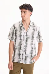 Camisa de manga corta con estampado tie-dye en tonos verdes y blancos, cuello cubano y cierre frontal con botones.