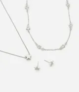 Conjunto de bisutería color plateado compuesto por dos collares de cadena fina y un par de aros tipo topo. Uno de los collares presenta múltiples dijes de estrellas pequeñas con incrustaciones de zirconia, mientras que el otro collar incluye un dije central de estrella lisa. Los aros tienen forma de estrella pequeña.