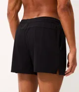 Bermuda de running Get Over para hombre, confeccionada en microfibra ligera de color gris claro. Presenta cintura elástica con cordón ajustable, bolsillos funcionales, dobladillo redondeado con aberturas laterales y pequeño parche con logo de la marca en la pierna izquierda.