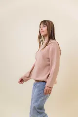 Sweater tejido de punto color blanco, con cuello alto y diseño en relieve tipo chevron en la parte frontal. Presenta un calce holgado con terminaciones acanaladas en puños y ruedo.