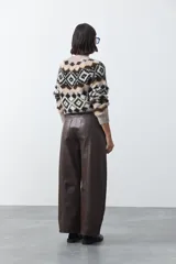 Pantalón de cuero sintético con fit barrel, de silueta amplia con volumen en las piernas y botamanga levemente entallada. Presenta bolsillos laterales y cierre frontal.