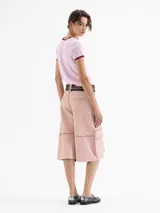 Bermuda de cuero ovino color rosa pálido con efecto 'brush off' (costuras y bordes desgastados en tono rojizo). Presenta un corte ancho y bolsillos cargo grandes en los laterales. Incluye dos cinturones finos ajustables con hebillas de metal.