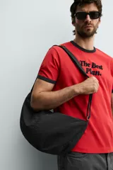 Bolso de hombro tipo hobo de nylon negro, con diseño curvo y asa ajustable. Cuenta con compartimento principal con cierre de cremallera y bolsillo interior con cremallera.